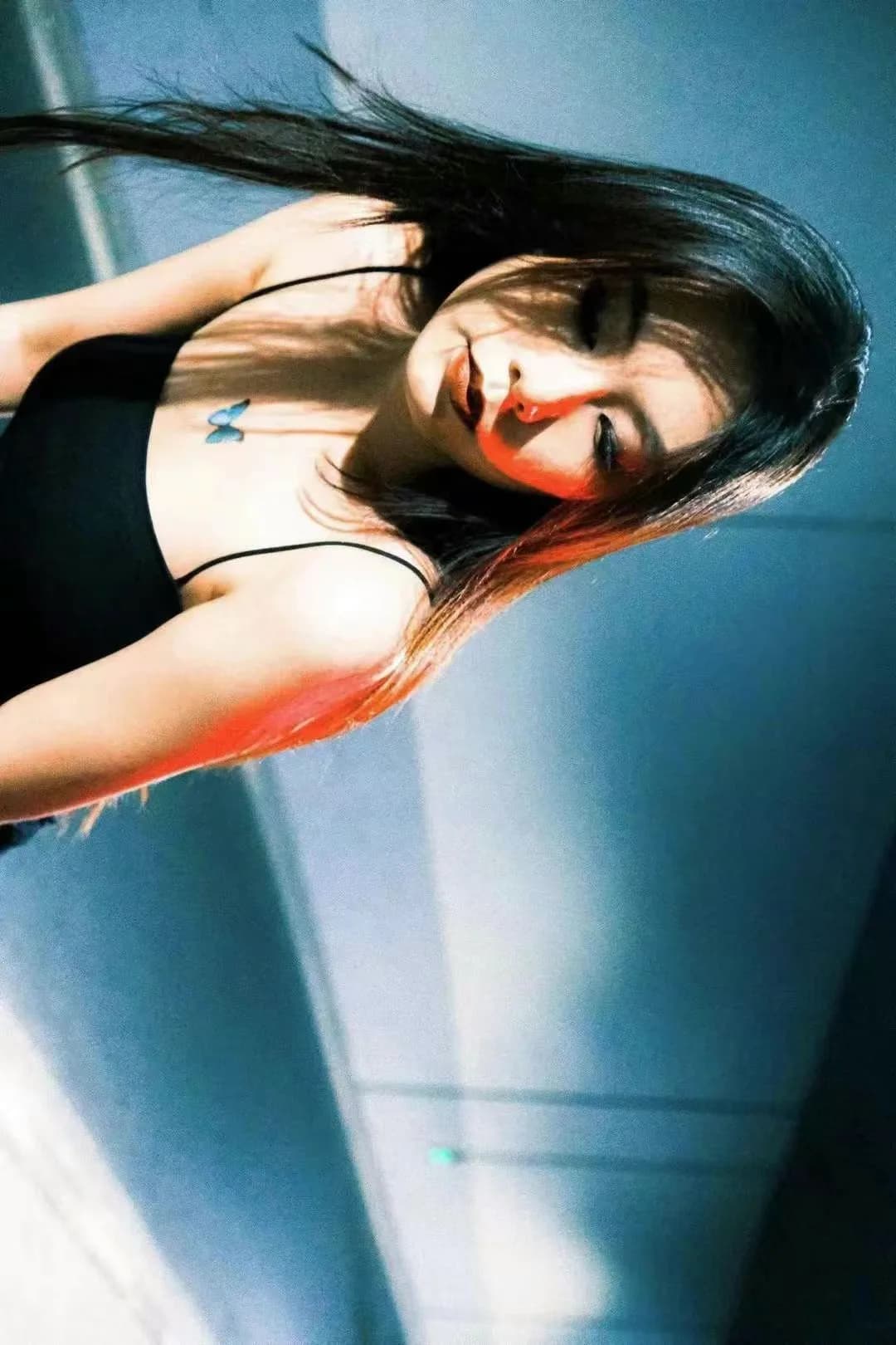 A tilted portrait against a cyan wall.