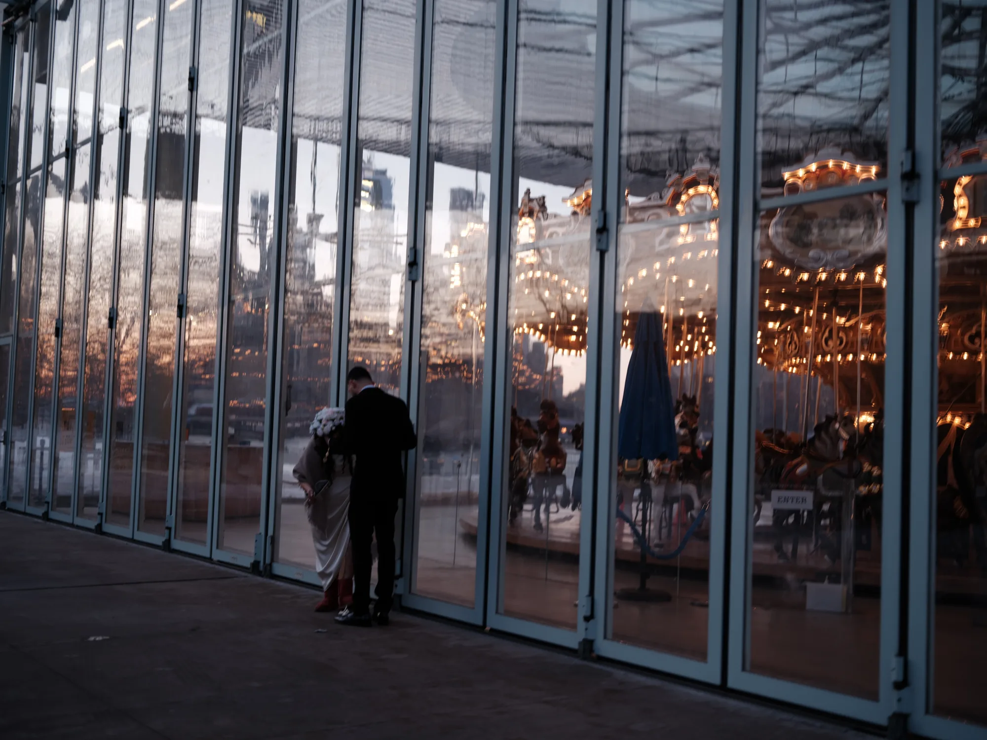 Figures outside a glass building at dusk.